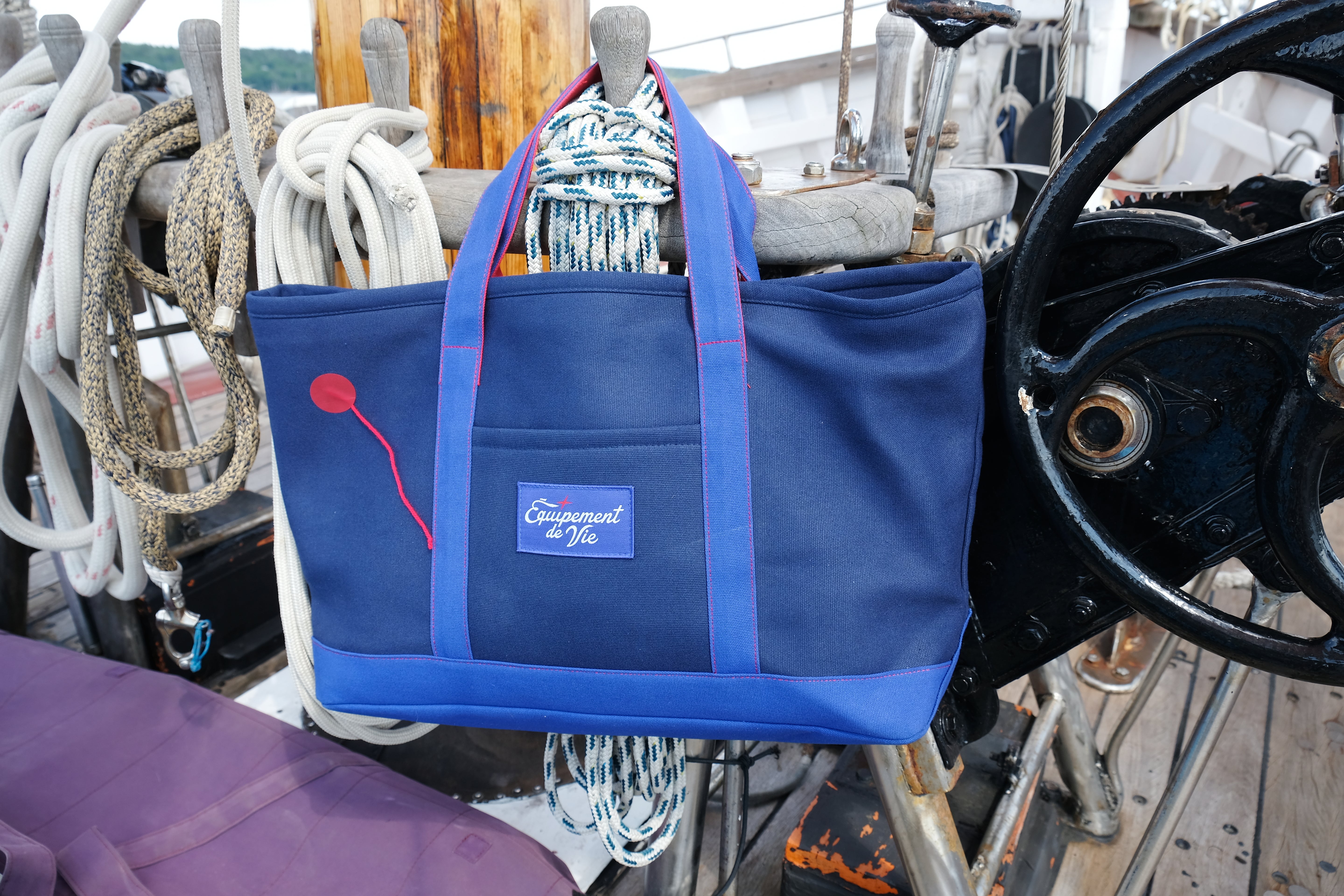 16oz Canvas Crew Tote in Navy and Royal hanging from the pin rail of a classic yacht
