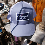 Trucker Cap in Dust Blue and Grey with Équipement De Vie patch, on deck of a classic yacht