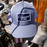 Trucker Cap in Dust Blue and Grey with Équipement De Vie patch, on deck of a classic yacht