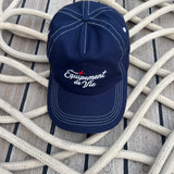 Contrast Stitch Cap in Navy laid on coiled rope on a teak deck