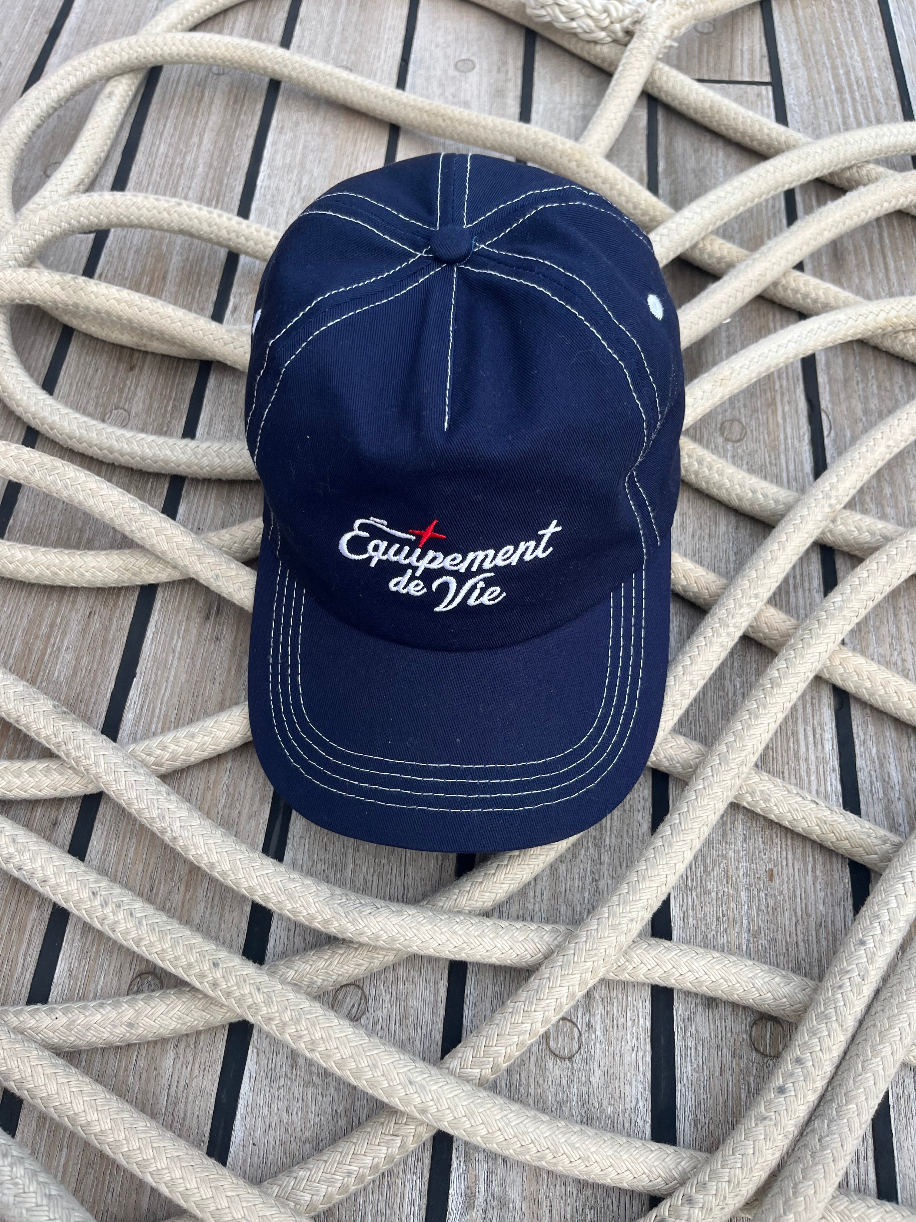 Contrast Stitch Cap in Navy laid on coiled rope on a teak deck
